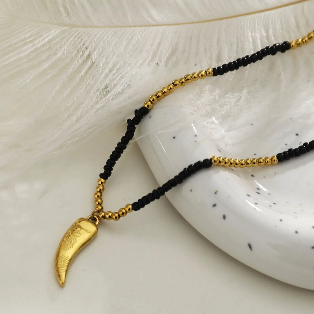 Collier RITA à chaîne perlée noir et or avec pendentif dent gravé en or