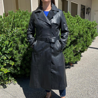Trench-coat classique en cuir pour femme. Double boutonnage avec ceinture ajustable.